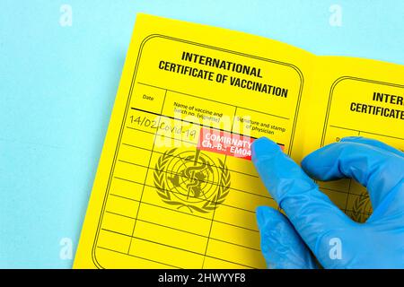 The doctor writes thirst booster vaccination against Covid 19 recorded in yellow vaccination certificate Stock Photo