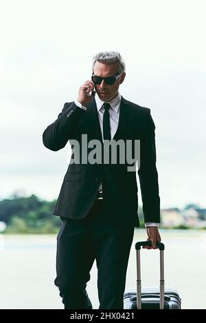 Ive just landed. Cropped shot of a handsome mature businessman walking with his luggage outside of the airport. Stock Photo