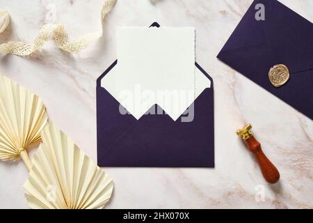 Purple envelopes, wedding invitation card mockup, ribbon, dried flowers on stone desk. Flat lay, top view, copy space Stock Photo