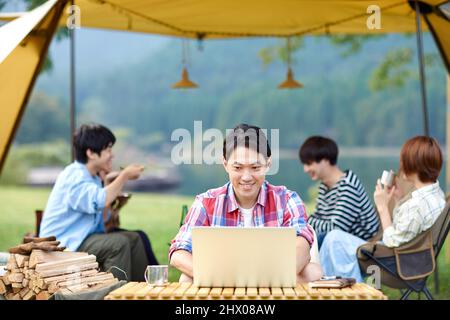 Japanese Men Teleworking At Campsite Stock Photo