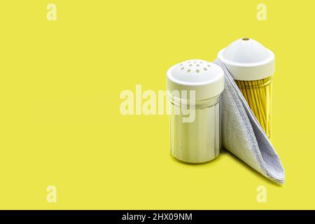 plastic salt shaker, napkin and toothpick holder, on yellow background, kitchen accessories with copyspace Stock Photo