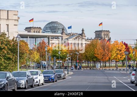 Berlin, Germany - October 18, 2021: The German Parliament Reichstag surrounded by colorful trees as seen from the Willi-Brandt Street with locals cros Stock Photo