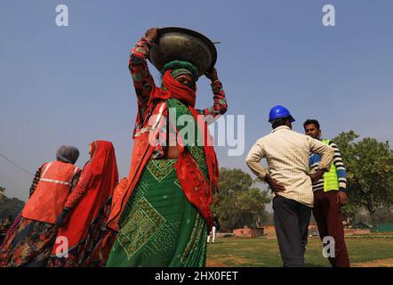 A female worker seen carrying a utensil filled with sand on her head on the occasion of International Women's Day in New Delhi. Stock Photo