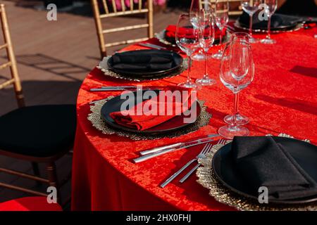 Guests table setting for banquet in black, red and gold style. Elegant and  luxury dinner arrangement: decor, tablecloth, plates, glasses, napkins,  cutlery. Themed birthday or wedding party celebration Stock Photo - Alamy