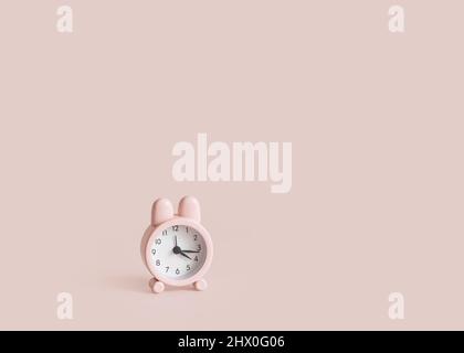Little pink bunny alarm clock on pink background. Easter minimal concept. Easter time. Copy space. Stock Photo