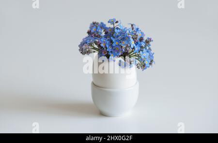 Small white egg with flowers bouquet on a white background. Easter egg. Space for text. Stock Photo