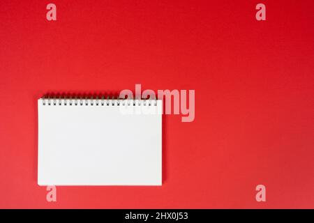 a blank spiral notebook on a red background Stock Photo