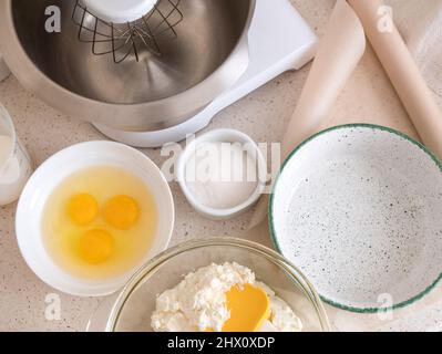 Ingredients and kitchen utensil for homemade cake on the kitchen table. Home cooking during lockdown, top view Stock Photo