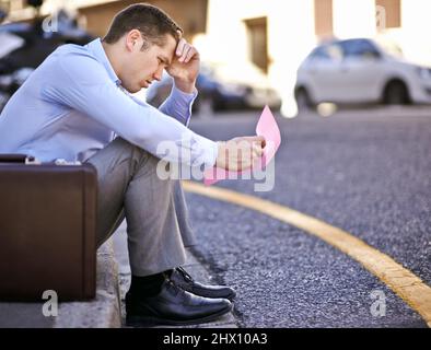 I never thought this would happen to me. A businessman holding a pink slip terminating his employment. Stock Photo