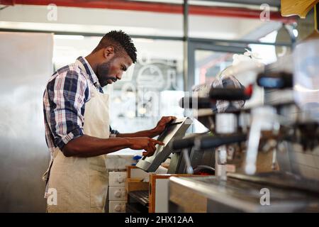 Busy day at the cafe. Cropped shot of a handsome male barista working in a coffee shop. Stock Photo