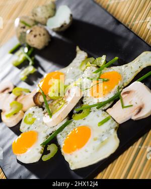 Broken fried quail eggs with mushrooms Stock Photo