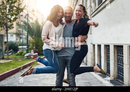 We have a good time doing anything. Shot of three friends having fun while out in the city. Stock Photo