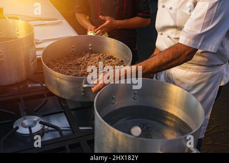 Professional chef giving classes to his student who serves as an assistant Stock Photo