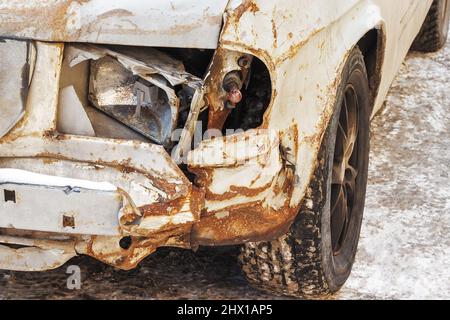 Broken headlight and corrosion of metal on an old car. The clunkers on the streets of a city. Stock Photo