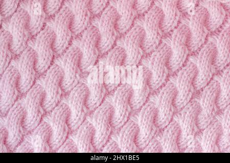 Knitted fabric made of wool yarn pink color. Pattern 'spit' associated knitting needles, handmade. Background texture. Stock Photo