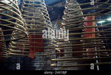 Multiple large yellow incense coils hanging in stacks from the Ceiling in a Chinese shrine. Large Bell Shaped Spiral Incense Coils, Focus and blur. Stock Photo