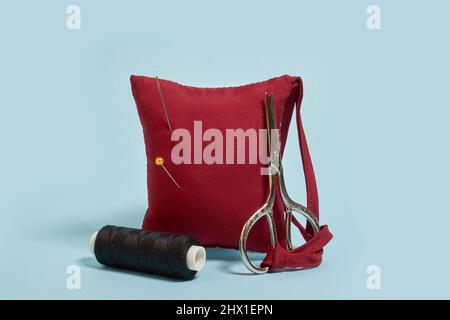 Sewing accessories. A needle pad, scissors and a spool of black thread  Stock Photo