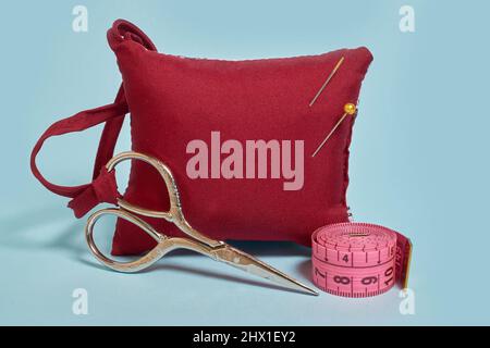 A needle pad, scissors and a tailor 's meter on a blue background Stock Photo