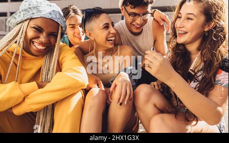 Multiethnic group of friends having fun together. Group of generation z friends laughing cheerfully while hanging out together outdoors in the city. H Stock Photo