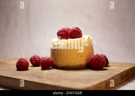 small raspberry portion cheesecake with raspberries seen from the front on rustic board Stock Photo