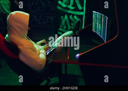 Hacker in hoodie working hacks code site on personal computer Stock Photo