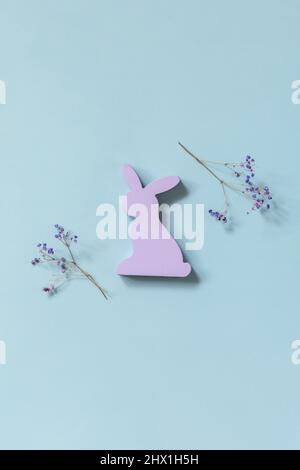 Happy Easter concept with purple rabbit, gypsophila flowers on a blue background. Easter background. Stock Photo