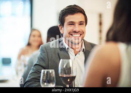 Hes head over heels. Cropped shot of an affectionate young man smiling broadly while on a date with his girlfriend in a restaurant. Stock Photo