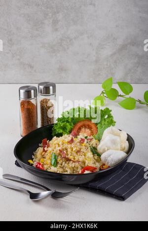 spicy asian fried rice stir fry with beef, slice fresh red tomato, fresh green lettuce and white crackers in black oval plate with blue napkin Stock Photo