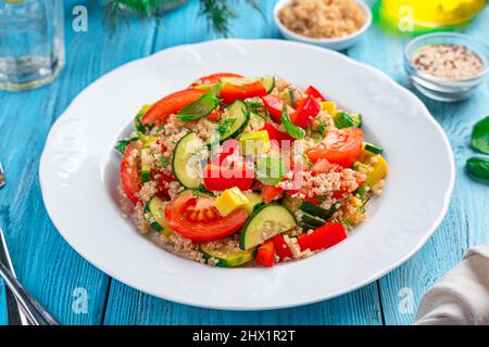 Tabbouleh salad with avocado and quinoa on a blue background. Vegetarian healthy salad. Side view, close-up. Stock Photo