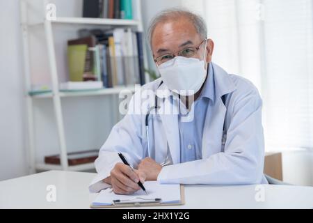 old doctor wearing fascmask sit on table preparing to taking the patient's history Stock Photo