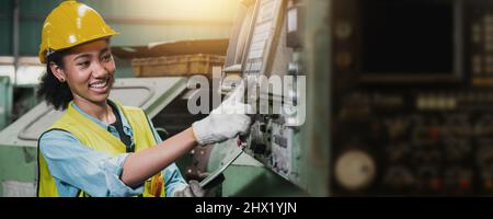 Happy African engineer woman working and checking machine in factory Stock Photo