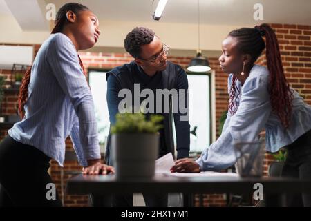 African american business company colleagues in meeting about startup project financial status. Marketing agency team members reviewing accounting documentation and revenue statistics data. Stock Photo