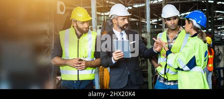 Industrial engineer and businessman in safety helmet working in factory, planning, discussing and training workers with tablet in metalwork place , te Stock Photo
