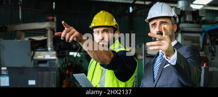 Industrial engineer and businessman in safety helmet working in factory, planning, discussing and training workers with tablet in metalwork place , te Stock Photo