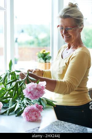She loves flowers. A happy senior woman making a bouquet of flowers. Stock Photo