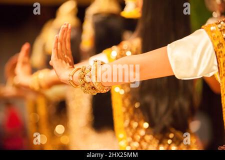 Graceful hands of Khmer Apsara dancers in traditional costume performs classical Khmer dance, bright golden glittering in the background. Cambodia. Stock Photo