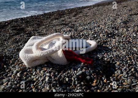 a bag with a laptop and a bottle of champagne lies on the coast of the sea Stock Photo