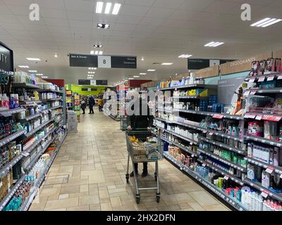 Waitrose Rushden Lakes Northamptonshire UK lady shopping basket trolley drinks liquid pushing rack racking racks buy buying inside lighting light Stock Photo