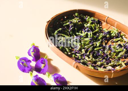 Bunga Telang Kering or Dried Butterfly Pea Flowers on woven bamboo plate. Isolated background. Stock Photo