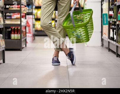 Fill it up. Cropped image of a young mans legs and grocery basket. Stock Photo