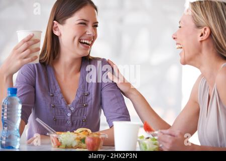 Lunch break bonding. Shot of two colleagues having lunch together. Stock Photo