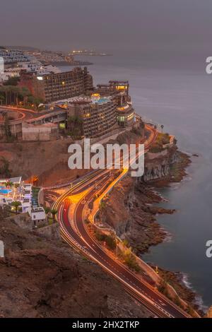 View of coastal road and hotels near Puerto Rico at dusk, Playa de Puerto Rico, Gran Canaria, Canary Islands, Spain, Europe Stock Photo