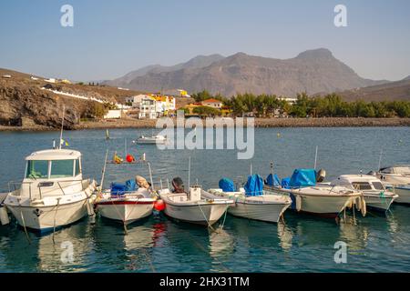 View of colourful boats in harbour and mountains in background, Puerto de La Aldea, Gran Canaria, Canary Islands, Spain, Europe Stock Photo