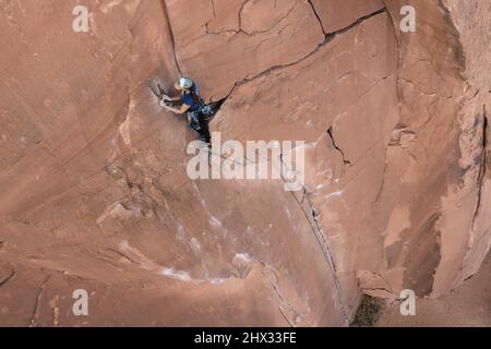 A female lead climber sets up a rope anchor at the top of the Flakes of Wrath, Wall Street near Moab, Utah. Stock Photo