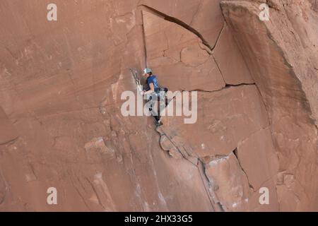 A female lead climber sets up a rope anchor at the top of the Flakes of Wrath, Wall Street near Moab, Utah. Stock Photo