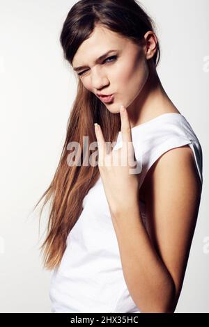 Rock on. A funky young beauty giving you devil horns and pouting with attitude. Stock Photo