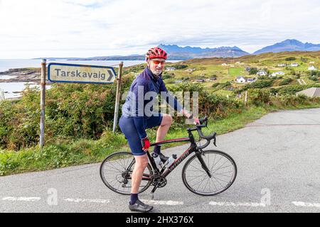 A cyclist at the village of Tarskavaig on Tarskavaig Bay on the Sleat Penisula in the south of the Isle of Skye, Highland, Scotland UK. The Cuillins a