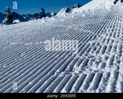 a close up of freshly groomed snow slope and the sky is cloudless and blue Stock Photo