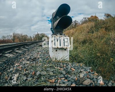 Signaling device or traffic light signal on railway. Turn of railway track. Iron rails in countryside. Stock Photo