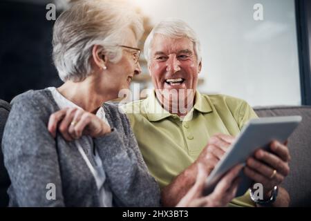 Its a laugh a minute on the internet. Shot of a senior couple using a digital tablet together on the sofa at home. Stock Photo